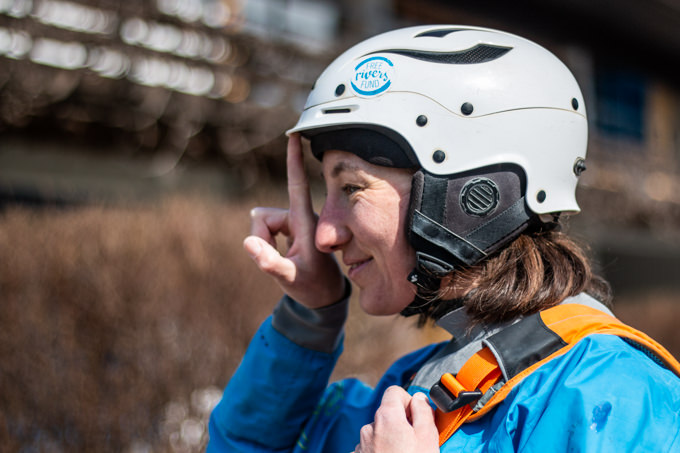 A woman tries to push her helmet back at the front of her forehead.