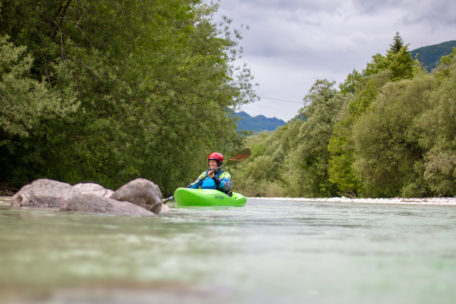 Kajakfahrerin am Fluss mit baumbewachsenem Ufer